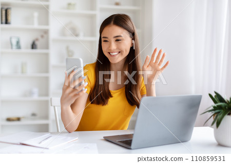 Asian Woman Making Video Call On Smartphone While Sitting In Home Office 110859531