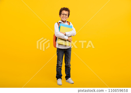 Schoolboy with glasses and school supplies on yellow background Schoolboy with glasses and school supplies on yellow background 110859658