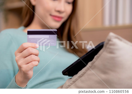 Young asian woman sitting on sofa using digital tablet shopping online with credit card. 110860556