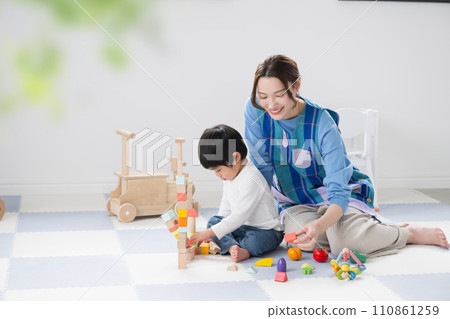 Toddlers and nursery school teacher playing with building blocks 110861259