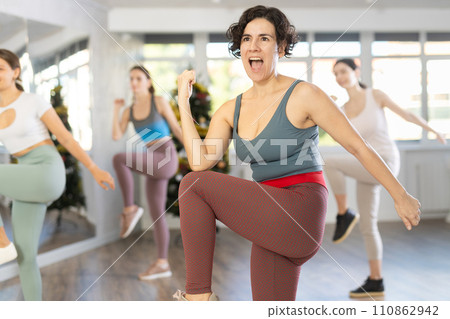 Hispanic female fitness instructor leading Zumba class in Christmas studio 110862942