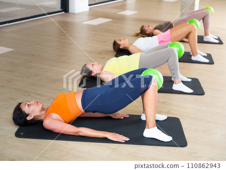 Women doing hip bridge with pilates ball 110862943