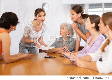 Positive young woman discussing with group of female volunteers 110862944