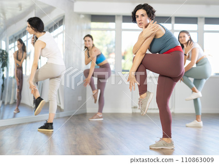 Sporty woman dancing modern dance at class with his friends Sporty woman dancing modern dance at class with his friends 110863009