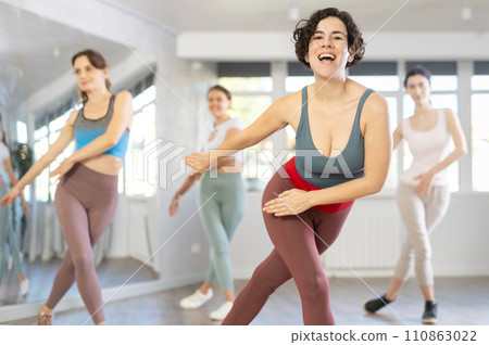 Cheerful Latina leading upbeat Zumba class for women in studio Cheerful Latina leading upbeat Zumba class for women in studio 110863022