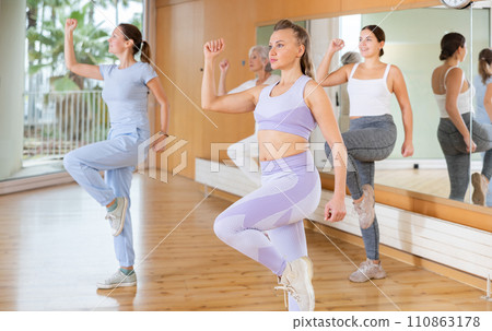 Active middle-aged woman practicing aerobic dance in training hall 110863178