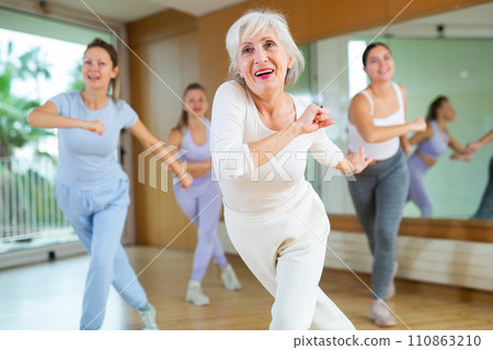 Dynamic elderly woman practicing aerobic dance in training hall 110863210