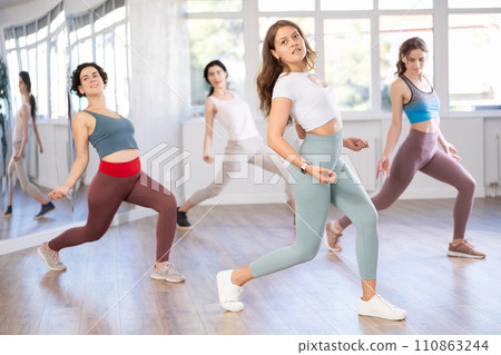 Young female teacher conducts modern hip hop dance lessons for group of girls 110863244