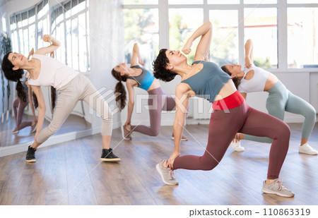 Hispanic woman learning modern street dancing during group class Hispanic woman learning modern street dancing during group class 110863319