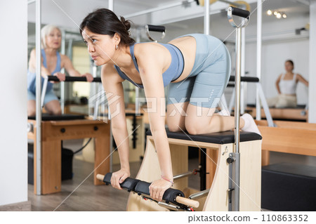 Young positive woman doing Pilates on special equipment in gym 110863352