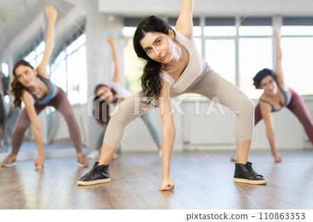 Active females exercising dance moves in modern dance studio Active females exercising dance moves in modern dance studio 110863353