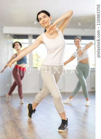 Young female teacher conducts modern dance lessons for group of girls Young female teacher conducts modern dance lessons for group of girls 110863358