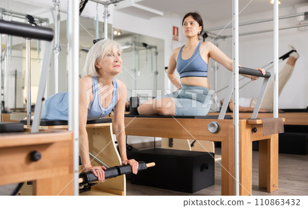 Elderly woman in sportswear training pilates performer bed in gym 110863432