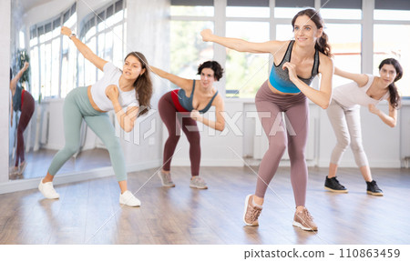 Emotional female dancer rehearsing popping techniques during group workout 110863459