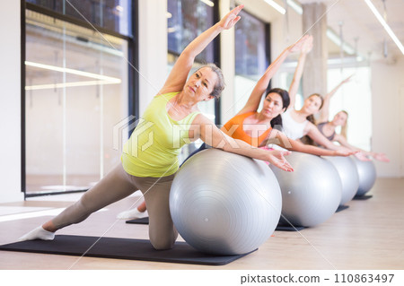 Pilates women fitball side bend exercise workout at gym 110863497