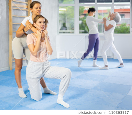 Young woman performing chokehold on female partner during self-defense training 110863517