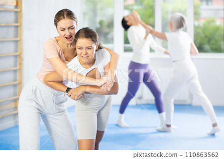 Woman and girl in gym perform basic elements of krav maga self-defense system. Woman and girl in gym perform basic elements of krav maga self-defense system. 110863562