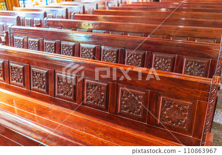 Empty wooden church benches of a Christian church. Blurry alter in the background. Selective focus. Concept of church service or empty churches. Empty wooden church benches of a Christian church. Blurry alter in the background. Selective focus. Concept of church service or empty churches. 110863967