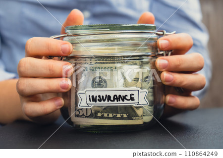 Unrecognizable woman holding Saving Money In Glass Jar filled with Dollars banknotes. INSURANCE transcription in front of jar. Managing personal finances extra income for future insecurity Unrecognizable woman holding Saving Money In Glass Jar filled with Dollars banknotes. INSURANCE transcription in front of jar. Managing personal finances extra income for future insecurity 110864249