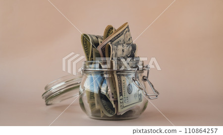 Dollar banknote saving money in glass jar. Consumption and economy Collecting money. Tips. Business, finance, saving, banking and people concept Dollar banknote saving money in glass jar. Consumption and economy Collecting money. Tips. Business, finance, saving, banking and people concept 110864257