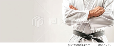 AI-generated content.  Martial artist in a white gi with black belt, standing confidently with arms crossed. 110865749
