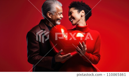 Beautiful couple holding big red glossy heart on red background. St Valentine's Day love. Beautiful couple holding big red glossy heart on red background. St Valentine's Day love. 110865861