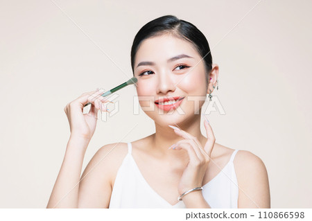 Beautiful and charming asian female applying a beautiful eyeshadow on her eyelid. Beautiful and charming asian female applying a beautiful eyeshadow on her eyelid. 110866598