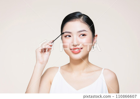 Closeup beautiful woman with eyebrow brush tool on beige 110866607