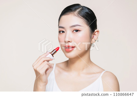 Beautiful young woman applying lipstick 110866647