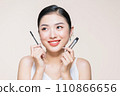 Beautiful asian young woman holding mascara and smiling on purple studio background, 110866656