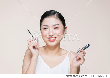 woman hold mascara isolated on beige background woman hold mascara isolated on beige background 110866661
