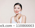 Young asian woman smile looking happy applying makeup with puff makeup on beige background. 110866663