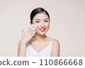 Young asian woman smile looking happy applying makeup with puff makeup on beige background. 110866668