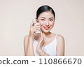 Young adult woman holds a glass of water in her hand near face 110866670
