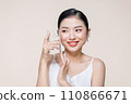 beautiful young asian woman with closed eyes holding glass of clear water near face 110866671