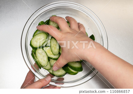 Making lightly pickled cucumbers - rubbing cucumbers with salt by hand 110866857