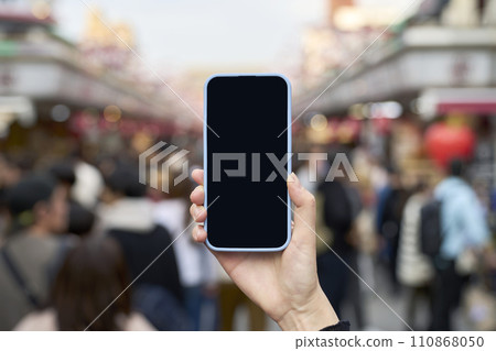 Crowded tourist spot and hand holding smartphone Crowded tourist spot and hand holding smartphone 110868050