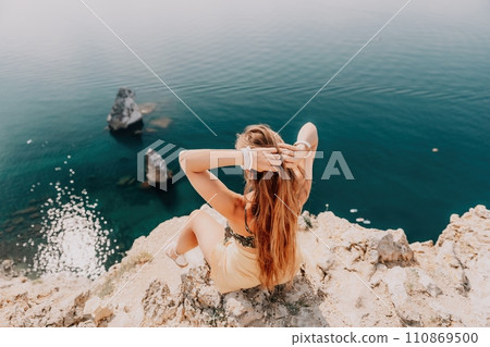 Woman travel sea. Happy tourist enjoy taking picture outdoors for memories. Woman traveler looks at the edge of the cliff on the sea bay of mountains, sharing travel adventure journey Woman travel sea. Happy tourist enjoy taking picture outdoors for memories. Woman traveler looks at the edge of the cliff on the sea bay of mountains, sharing travel adventure journey 110869500