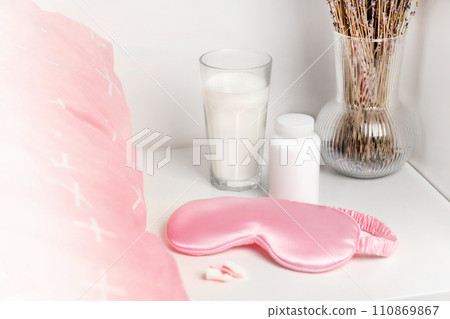 Bedside table with a silk sleep mask, earplugs and lavender and warm milk for a good night's sleep and sleeping pill mock up. All conditions for good deep sleep. Help for falling asleep free space Bedside table with a silk sleep mask, earplugs and lavender and warm milk for a good night's sleep and sleeping pill mock up. All conditions for good deep sleep. Help for falling asleep free space 110869867