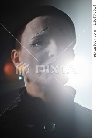 Dramatic closeup portrait of sad mime artist performing on stage with backlight Dramatic closeup portrait of sad mime artist performing on stage with backlight 110870014