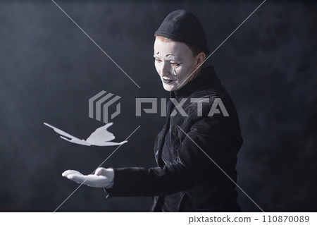 Waist up portrait of mime performer acting on stage in spotlight with paper butterfly, copy space 110870089