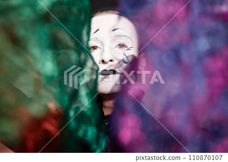 Dramatic close up portrait of mime performer looking at camera on stage in spotlight holding magic shimmering cloth, copy space Dramatic close up portrait of mime performer looking at camera on stage in spotlight holding magic shimmering cloth, copy space 110870107