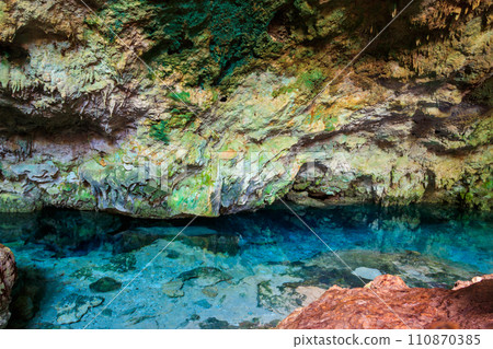 View of beautiful natural pool of crystal clear water formed in a rocky cave with stalagmites and stalagmites. Kuza cave in Zanzibar, Tanzania View of beautiful natural pool of crystal clear water formed in a rocky cave with stalagmites and stalagmites. Kuza cave in Zanzibar, Tanzania 110870385