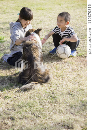 一個孩子在公園裡撫摸寵物（狗） 110870816