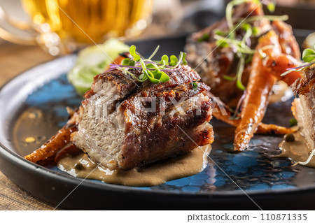 Three pieces of baked belly with grilled vegetables on a plate in a pub or restaurant Three pieces of baked belly with grilled vegetables on a plate in a pub or restaurant 110871335