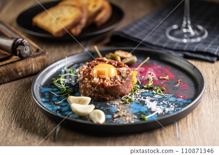 Beef tartare with egg yolk on a plate with garlic and toasted bread Beef tartare with egg yolk on a plate with garlic and toasted bread 110871346