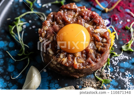Beef tartare with egg yolk on a plate with garlic and toasted bread Beef tartare with egg yolk on a plate with garlic and toasted bread 110871348