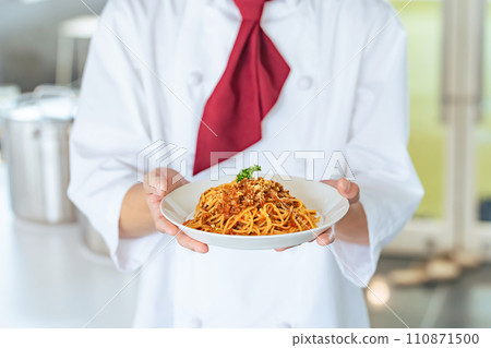 A man wearing a cook coat and carrying food 110871500