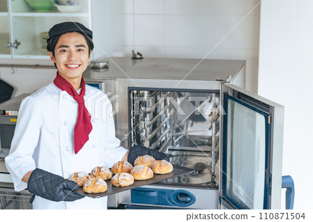 Baker taking bread out of the oven 110871504