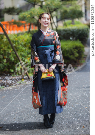A woman in a kimono looking at cherry blossoms 110871584